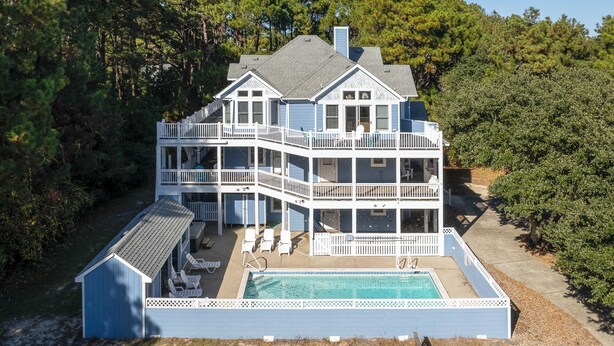 A multi-story house with a pool, surrounded by trees. - 12BR Retreat w/ Private Pool, Theater, Volleyball + Elevator | Perfect for Large Groups (Corolla)