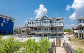 Ein mehrstöckiges Strandhaus mit Balkonen, einer Holzterrasse und freiem Blick auf das Meer.