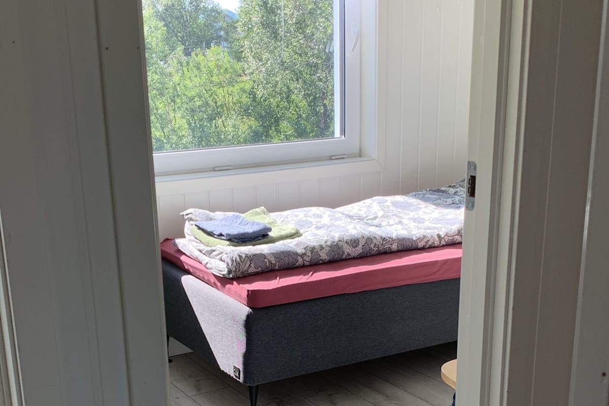 Une chambre à coucher avec un lit, une fenêtre et une vue sur les arbres.