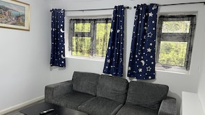 A room with a grey sofa, a black coffee table, and a painting on the wall. - Comfy 2-bedroom Apartment (Birmingham)