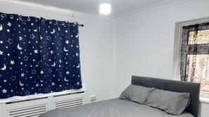 A bedroom with a bed, a window with a curtain, and a radiator. - Comfy 2-bedroom Apartment (Birmingham)
