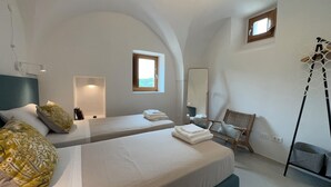 A hotel room with two beds, a chair, a mirror, and a window. - A Trullo Like No Other - Timeless Style, Modern Comforts. Private Pool (Selva di Fasano)