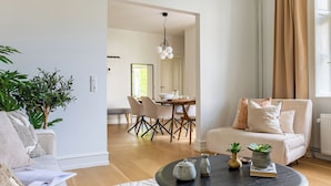Una sala de estar moderna con un sofá, una mesa redonda de centro y un área de comedor al fondo.