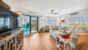 Amplia sala de estar con un sofá grande, una mesa de centro y un televisor. Hay un balcón con vista a la ciudad.