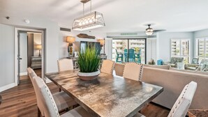 Un comedor con una mesa de madera, sillas tapizadas en color beige y una planta en maceta en el centro.