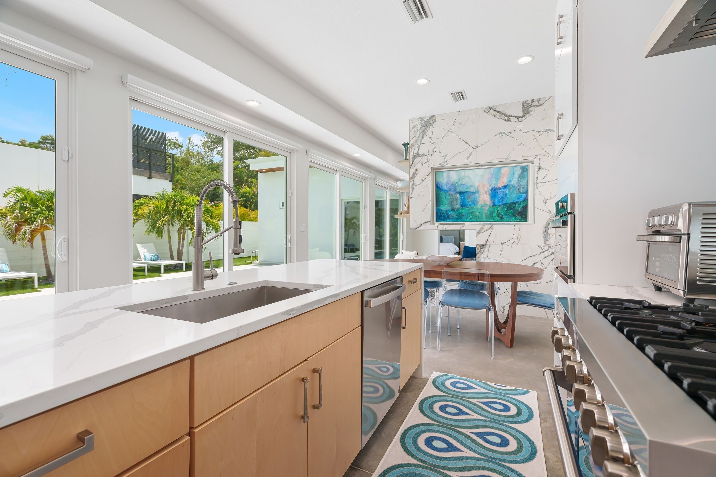 A modern kitchen with a large island, a built-in dishwasher, and a gas stove.