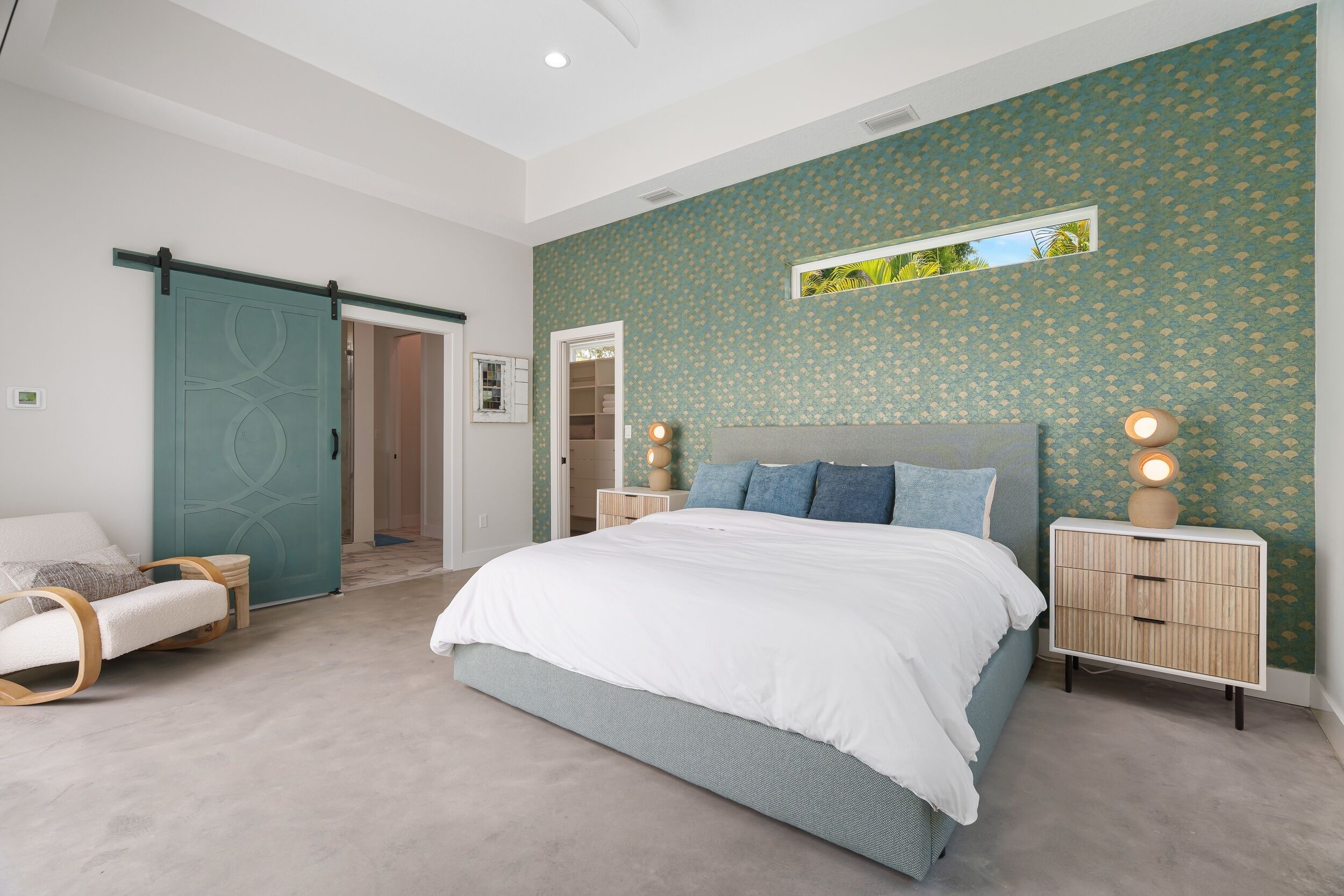 Une chambre à coucher comprenant un lit, une table de chevet, une chaise, une porte coulissante et une fenêtre.