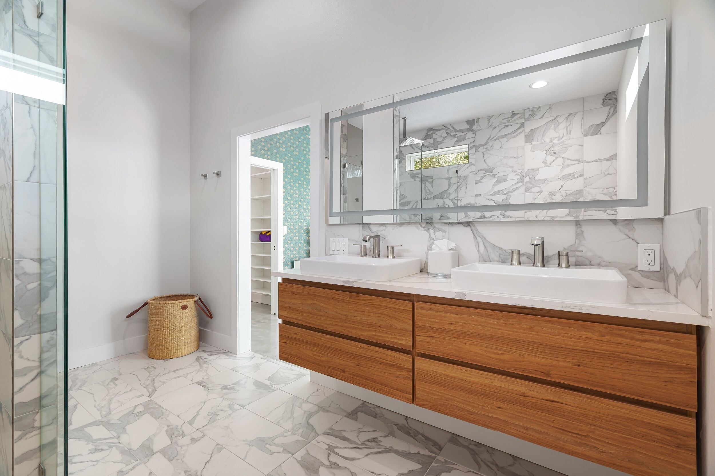 Un baño moderno con dos lavamanos, un espejo grande y una zona de ducha.