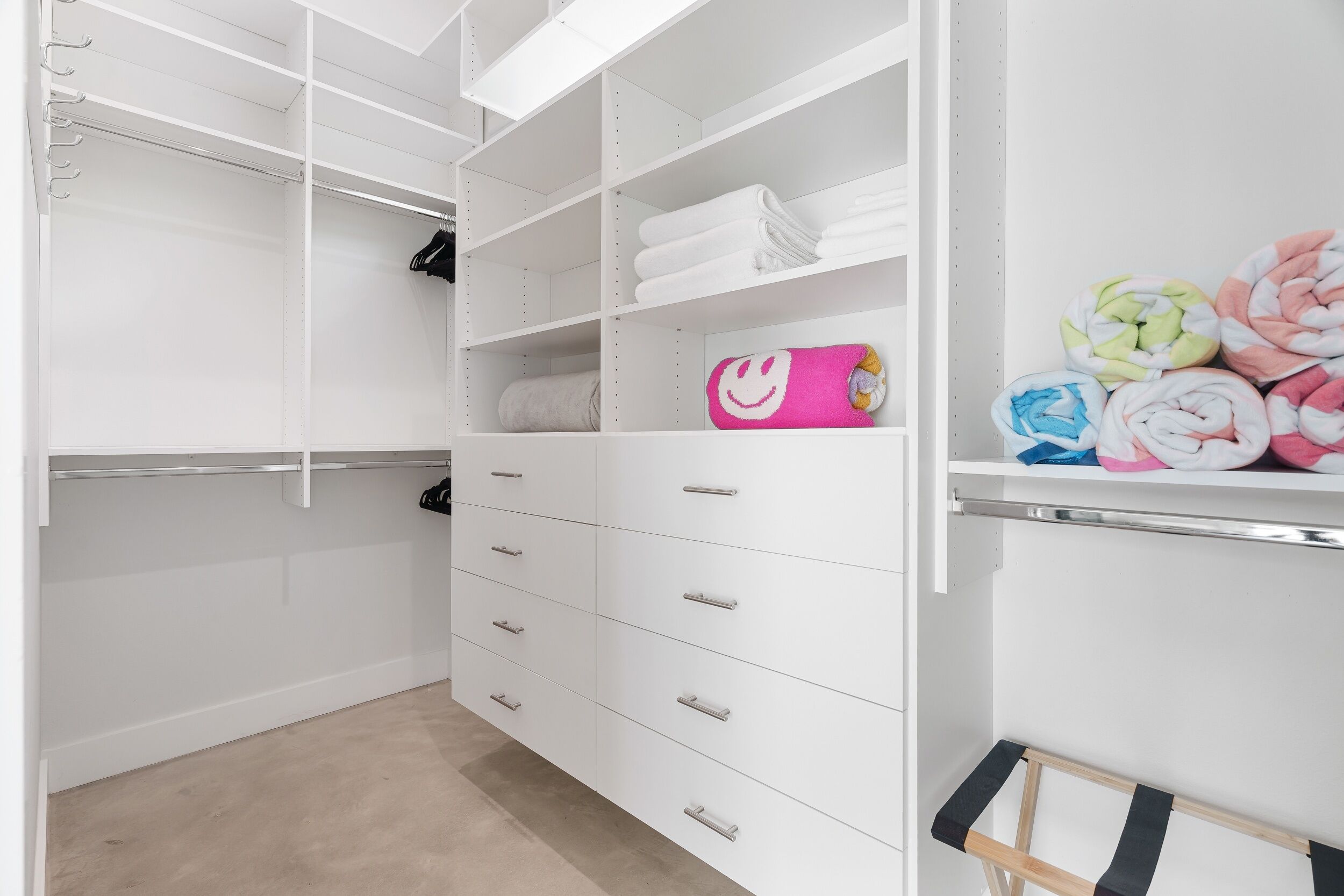 Un placard blanc doté de nombreuses étagères, de tiroirs et d’un espace pour suspendre les vêtements.