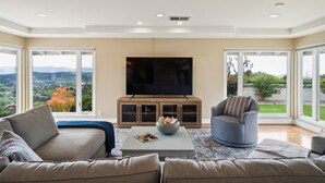 Un salon moderne doté d’un grand téléviseur à écran plat, de sièges confortables et offrant une vue sur l’extérieur.