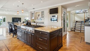 Une cuisine spacieuse dotée d’un grand îlot central, d’appareils électroménagers intégrés et d’un design moderne.