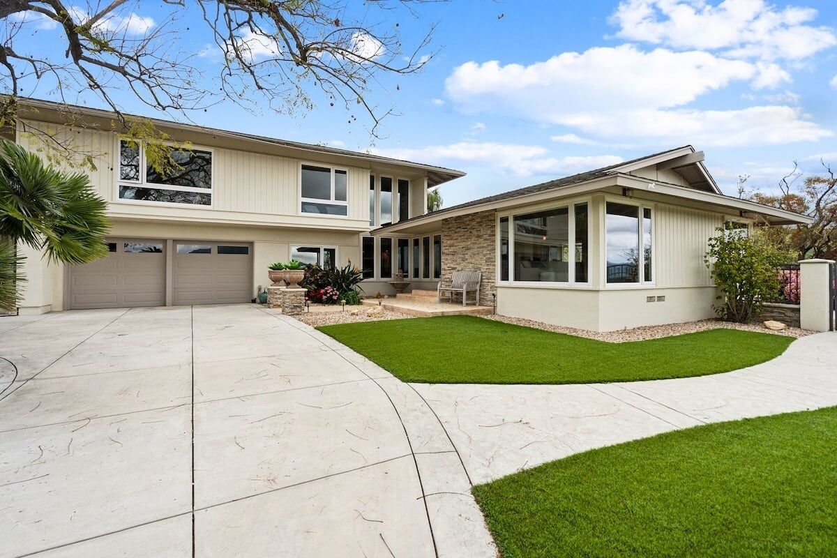 Ein zweistöckiges Haus mit Garage, überdachter Terrasse und gepflegtem Rasen.