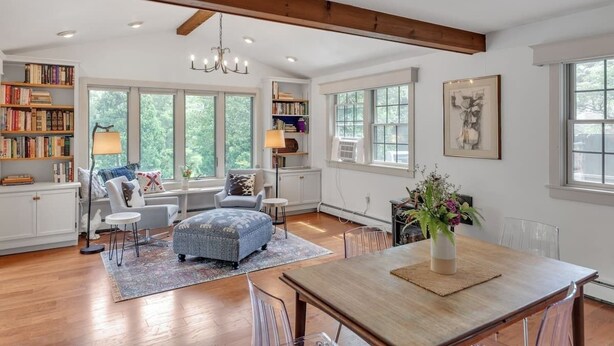 A spacious living room with a wooden ceiling, large windows, a dining area, and a bookshelf. - Bear Pass - Mountain View 4 Bedroom Home by RedAwning (Arlington)