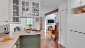 A modern kitchen with white cabinetry, a central island, and a wooden dining area. - Bear Pass - Mountain View 4 Bedroom Home by RedAwning (Arlington)