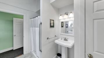 A bathroom with a shower, a sink, and a mirror.