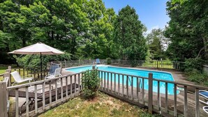 A backyard with a swimming pool, surrounded by a wooden deck and a fence. - Bear Pass - Mountain View 4 Bedroom Home by RedAwning (Arlington)