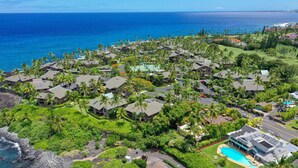 En semesteranläggning vid kusten med flera byggnader i bungalowstil, en central pool och utsikt över havet.