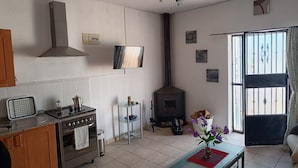 A living room with a built-in stove, a ceiling fan, and a large window with curtains. - The Terrance Principle Asturias 15 (Guadix)