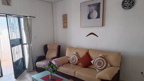 A living room with a beige sofa, two armchairs, a coffee table with a vase of flowers, and a framed picture on the wall. - The Terrance Principle Asturias 15 (Guadix)
