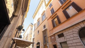 A narrow street with buildings featuring classic architecture, including arched doorways and decorative ironwork. - Amazing Domus Ruspoli  (Roma)
