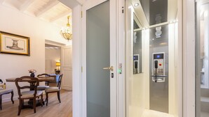 A modern interior with a dining area, a glass door leading to a bathroom, and a visible elevator. - Amazing Domus Ruspoli  (Roma)