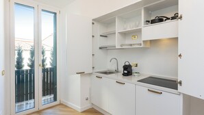 A compact kitchen with white cabinets, a sink, and a coffee maker. - Amazing Domus Ruspoli  (Roma)