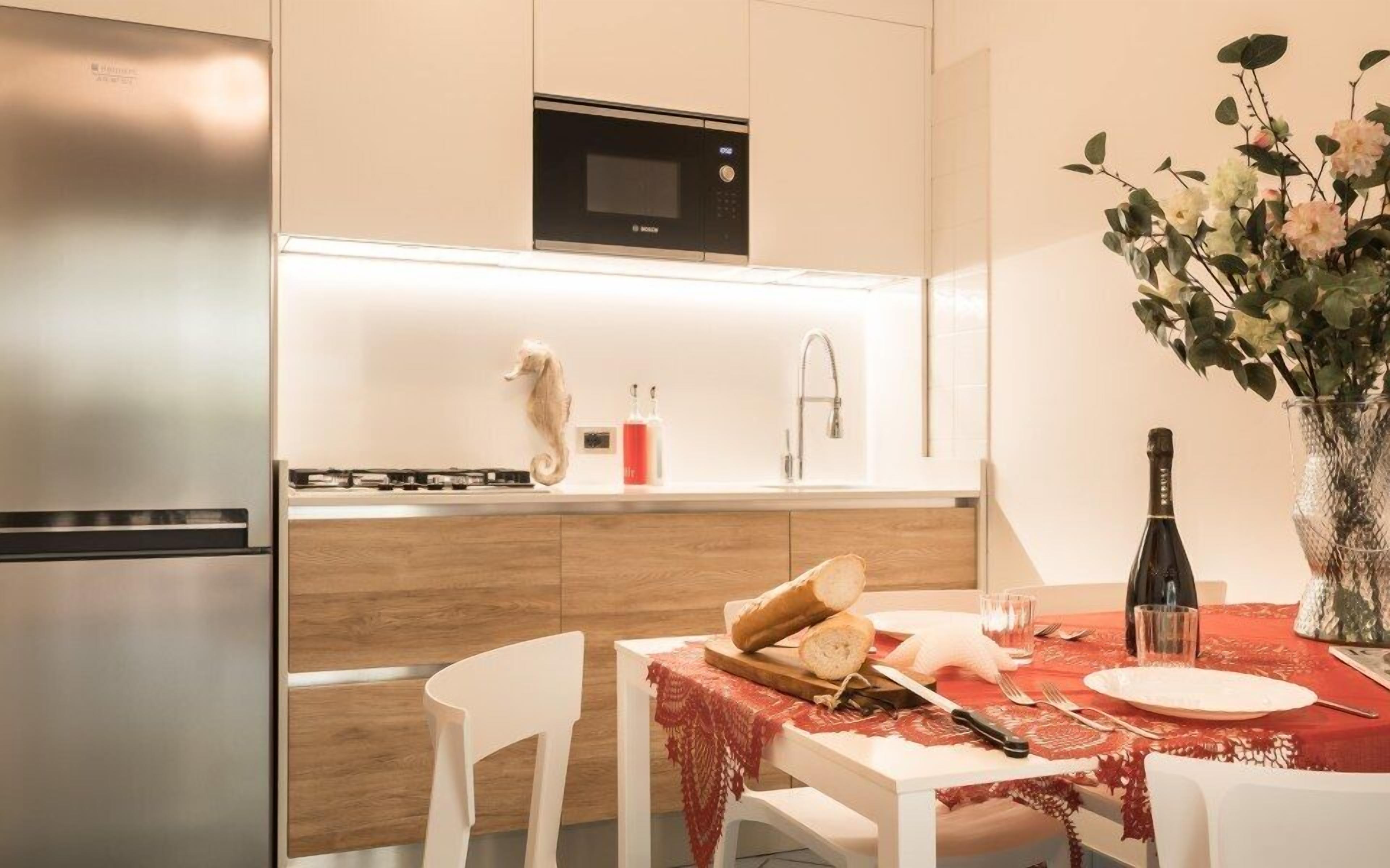 Una cocina moderna con microondas incorporado, un lavamanos y un comedor con una mesa, sillas y un florero.