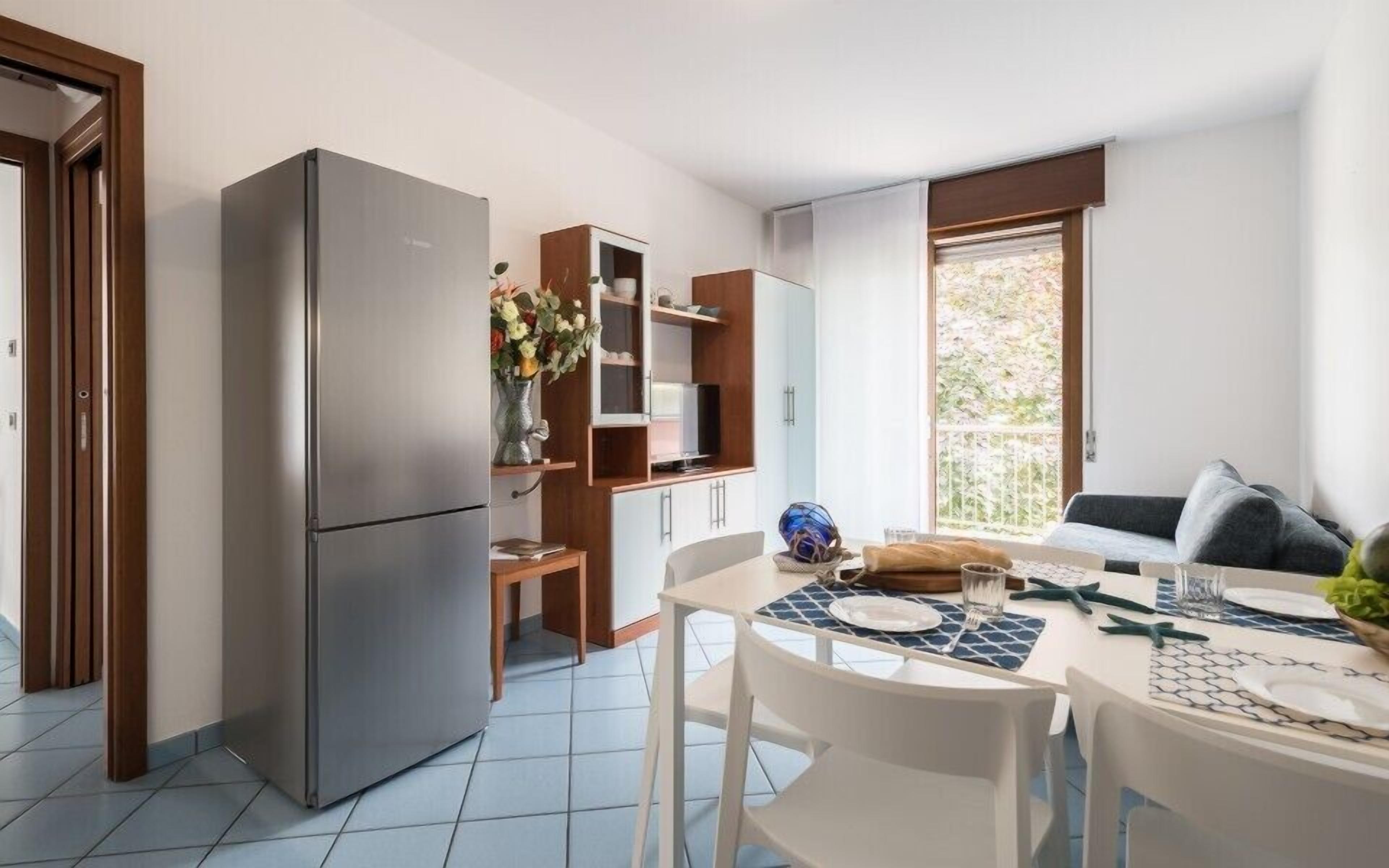 A compact kitchen with a refrigerator, wooden cabinets, and a dining area with a table set for two.