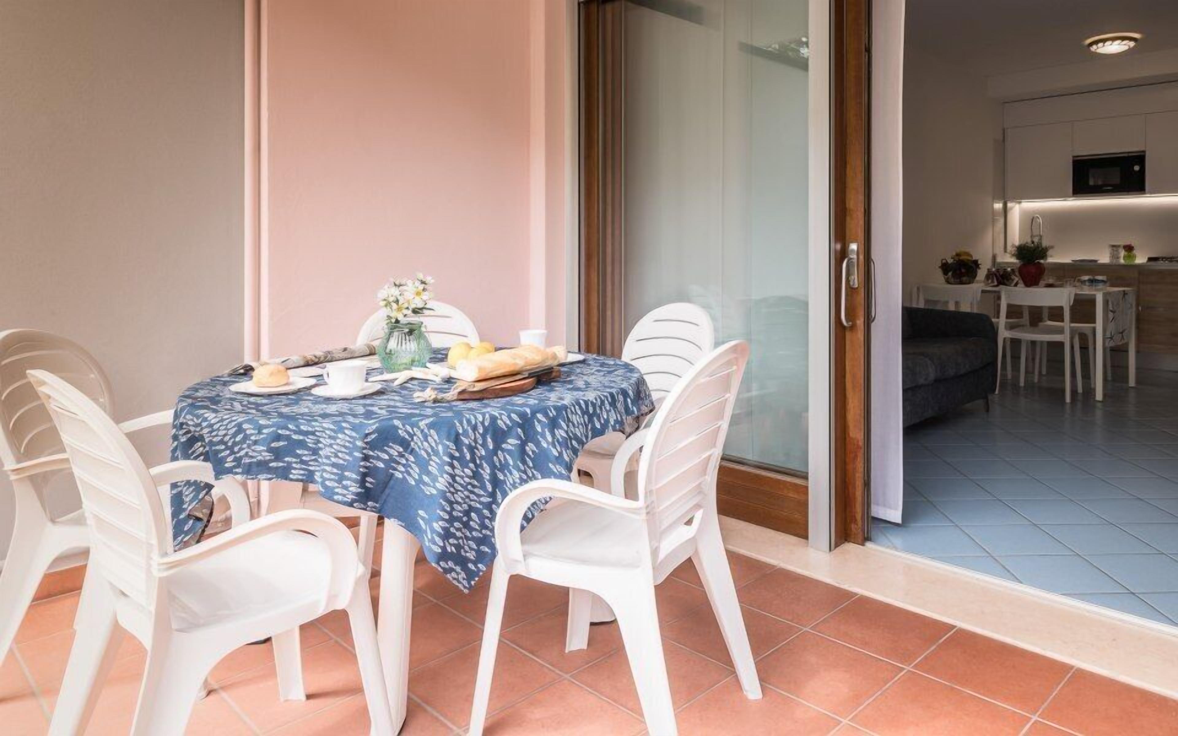 A dining area with a table set for two, white chairs, and a blue tablecloth.