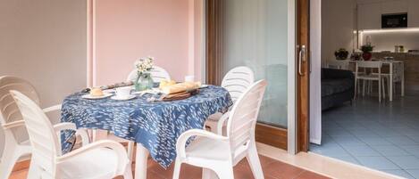 A dining area with a table set for two, white chairs, and a blue tablecloth.