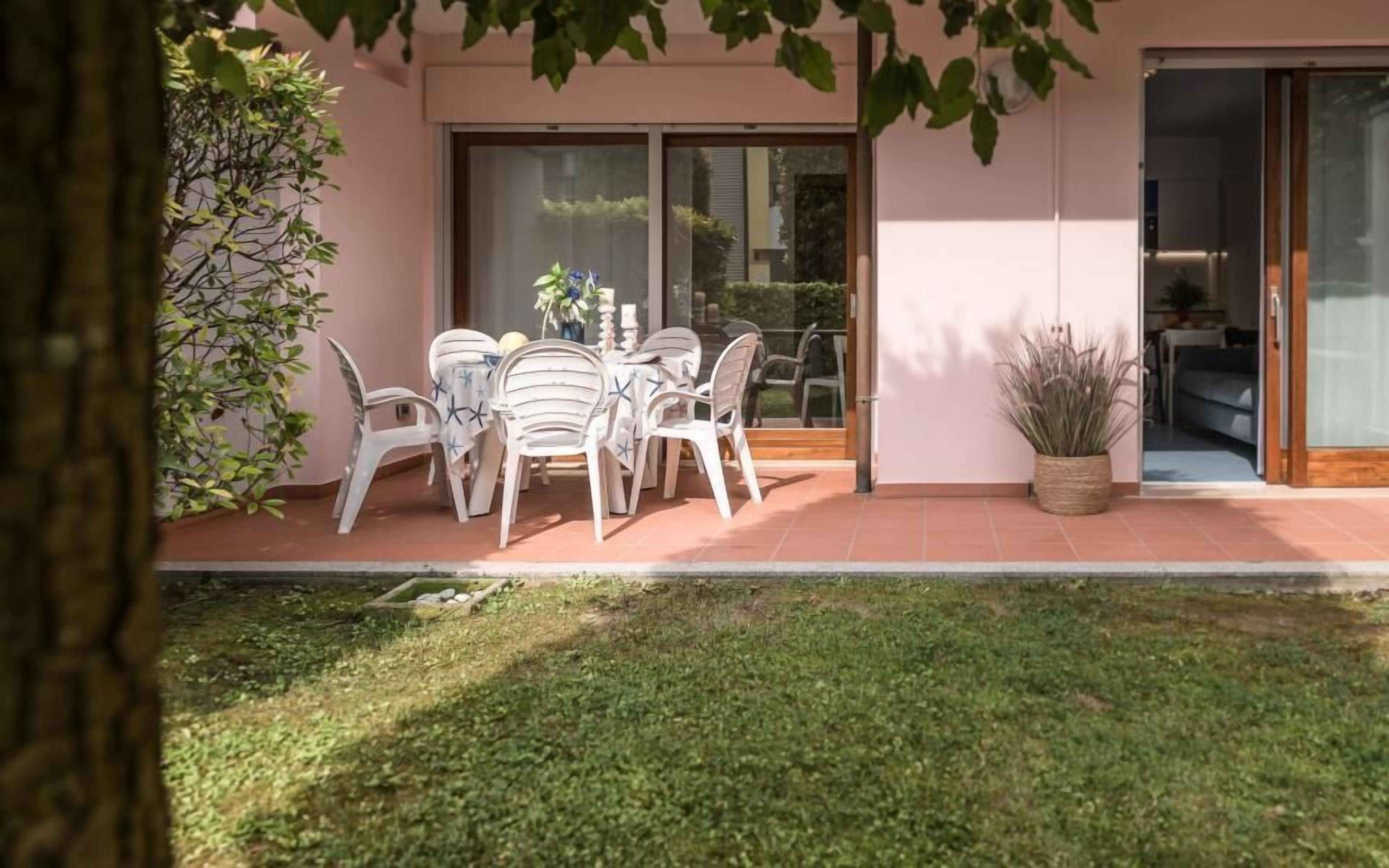 A patio with a table and chairs, a potted plant, and a sliding glass door leading to an interior space.