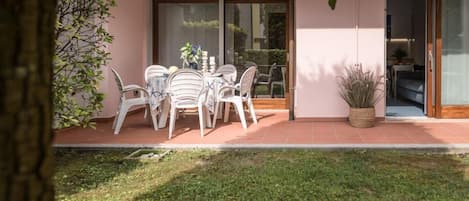 A patio with a table and chairs, a potted plant, and a sliding glass door leading to an interior space.