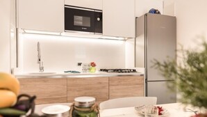 A modern kitchen with a built-in microwave, a stainless steel refrigerator, and a wooden countertop. - COSTA RICA BIBIONE Eco Resort (San Michele al Tagliamento)