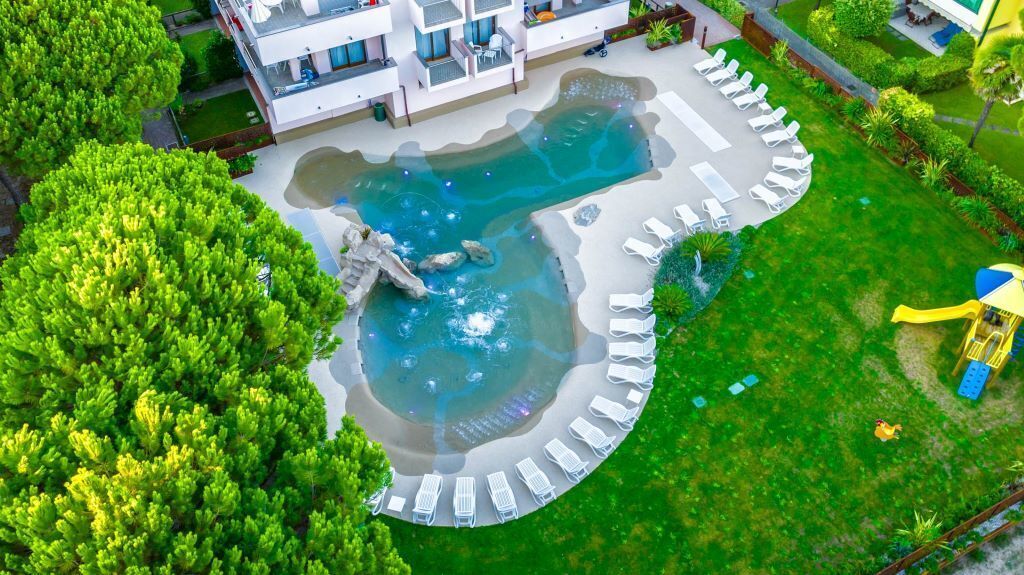 An aerial view of a hotel with a swimming pool, lounge chairs, and a playground.