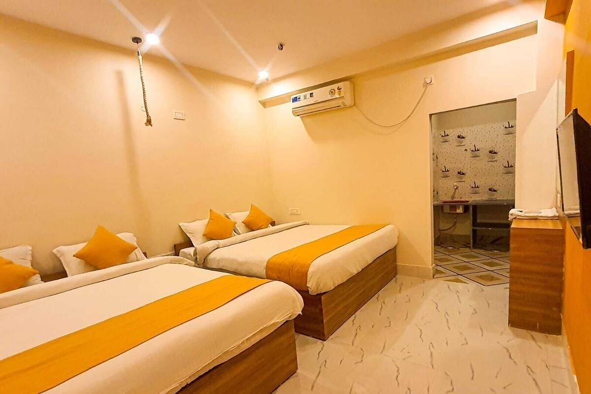A hotel room with two beds, a bathroom with a ship-themed wall, and a TV on the wall.