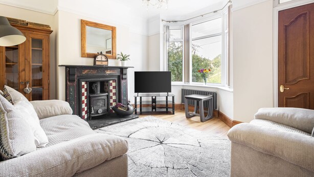 Una sala de estar con chimenea, televisor y un amplio ventanal.