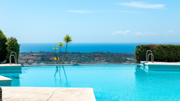 A clear blue swimming pool with a view of the ocean and distant landscape. - Bright 3BR with Sunset Views and Garden (Benahavís)