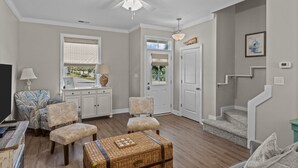Un salon équipé d’un ventilateur de plafond, d’une télévision, d’un canapé, d’un fauteuil, d’une table et d’un escalier.
