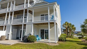 Une maison de deux étages située en bord de mer, dotée d’un porche couvert, de plusieurs balcons et d’une pelouse bien entretenue.