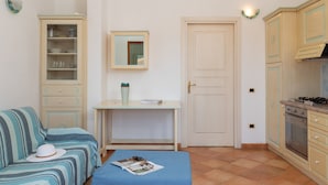 A compact kitchen with a dining area, a sofa, and a small table with a magazine.