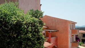 A residential building with a pink facade, a gated entrance, and a staircase leading to the upper floor.