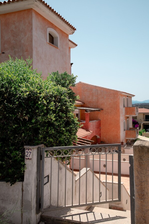 Un immeuble résidentiel à la façade rose, doté d’une entrée sécurisée et d’un escalier menant à l’étage supérieur.