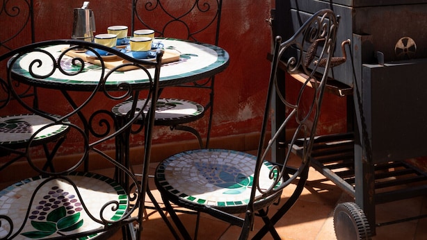 A terrace with a table and chairs, a grill, and a view of the landscape.