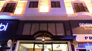 Un hotel con fachada moderna, grandes ventanales y un letrero que indica que es el 'Adah Boutique Hotel'.