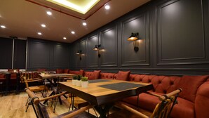 Un restaurante moderno con mesas de madera y asientos tapizados en rojo.