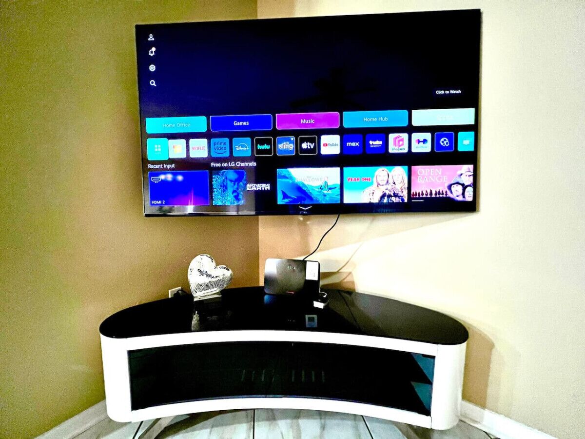 Ein Flachbildfernseher an der Wand über einem schwarz-weißen Lowboard.
