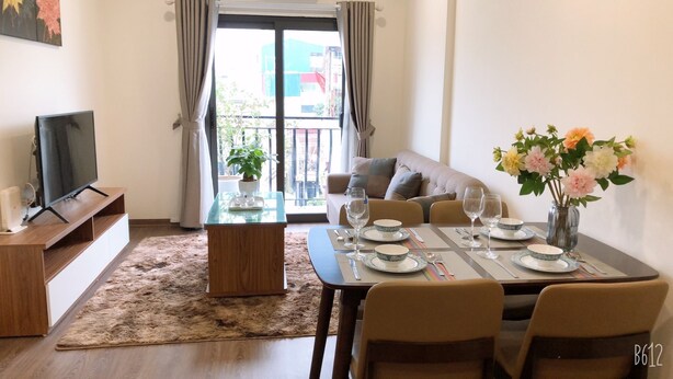 Zona pranzo con tavolo per quattro, divano, televisore e balcone con vista.