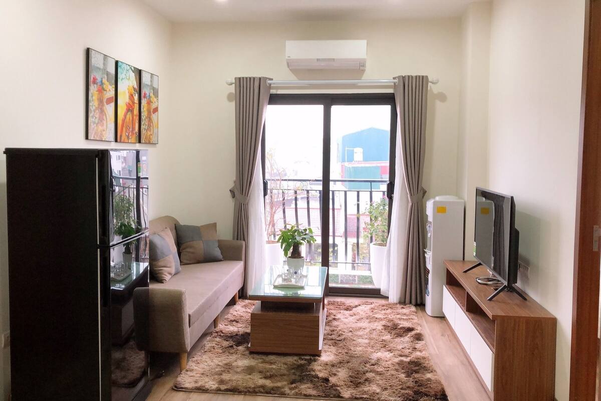A compact living space with a sofa, a coffee table, a TV, and a refrigerator.