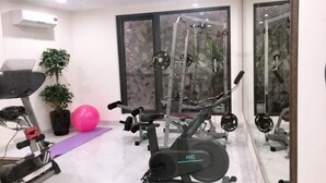 Una palestra in casa con attrezzature per esercizi, una palla da ginnastica rosa e un vaso con una pianta.