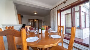 Comedor con mesa de madera para cuatro personas, chimenea y vistas a un balcón.